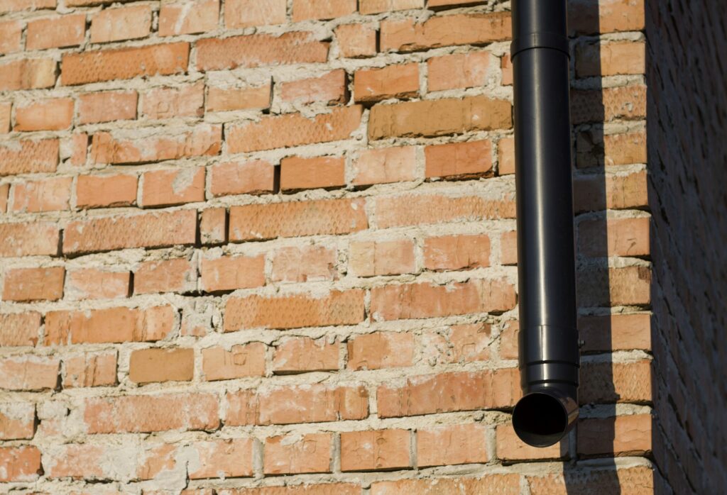 Detail of brick wall,, exterior corner of building with new drainpipe. Construction and rain sewage